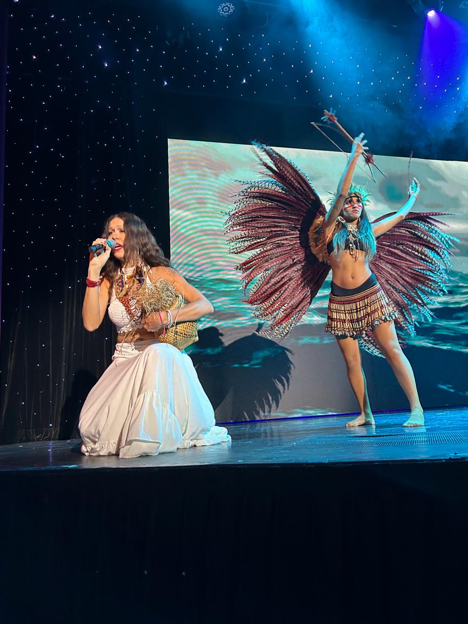 Grazi performing with a dramatic feather costume on stage